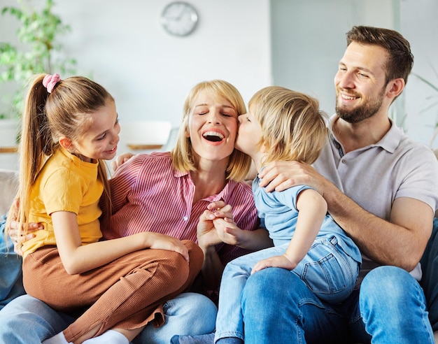 Child daughter son family happy mother father sofa playing fun together girl boy cheerful smiling home