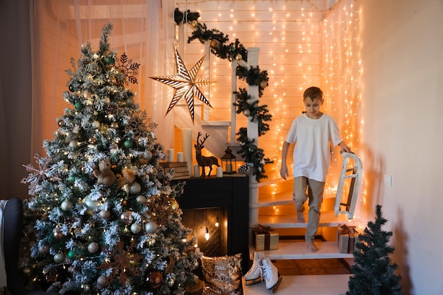 Child decorating Christmas tree at home. Little boy in knitted sweater with Xmas ornament. Family with kids celebrate winter holidays. Kids decorate living room and fireplace for Christmas.