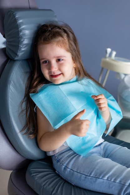 A child in a dental chair smiles at the camera