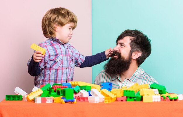 Child development father and son play game happy family leisure
time little boy with bearded man dad playing together building home
with colorful constructor love to play game play game time