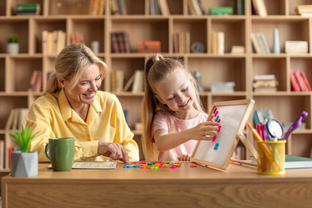 Scuola di sviluppo del bambino insegnante femminile professionista che si esercita con una bambina che fa parole con lettere colorate