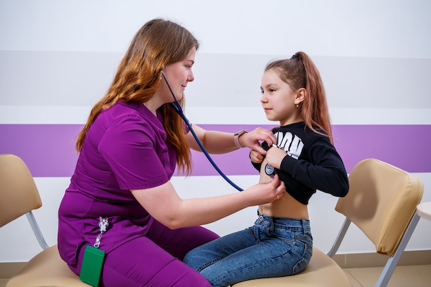 의사의 약속에 아이, 의사는 소녀를 검사하고, 체온을 측정하고, 호흡기를 확인합니다