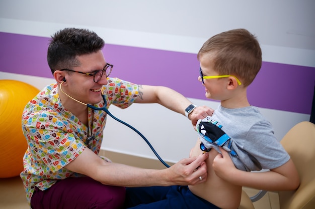 A child at the doctorâs office, the doctor listens to the boyâs lungs,