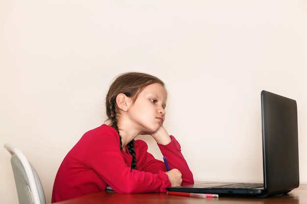 Child doing homework tired and leaned her head on her arm in front of laptop