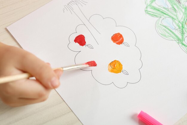 Photo child drawing tree with bright paints on paper closeup