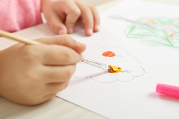 Child drawing tree with bright paints on paper closeup