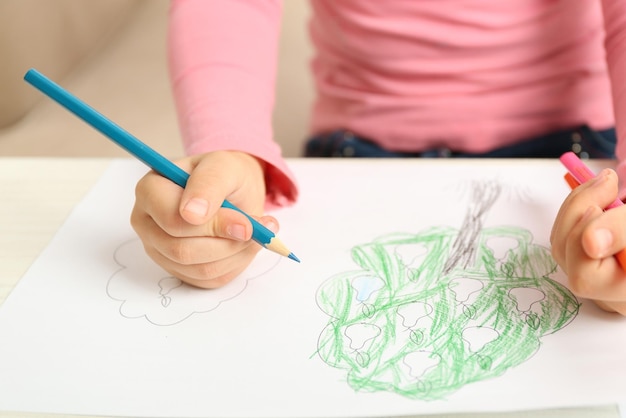 child drawing tree with pencils on paper closeup
