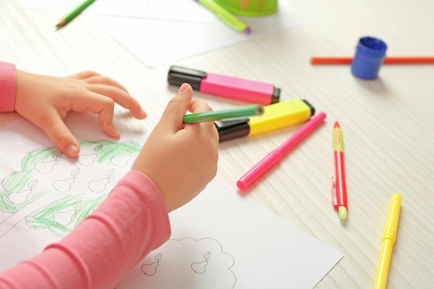 Child drawing tree with pencils on paper closeup