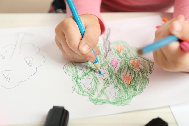 child drawing tree with pencils on paper closeup