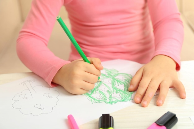 child drawing tree with pencils on paper closeup