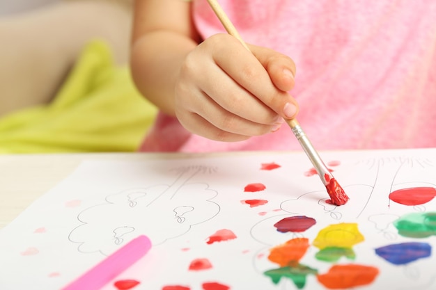 Photo child drawing with bright paints on paper closeup