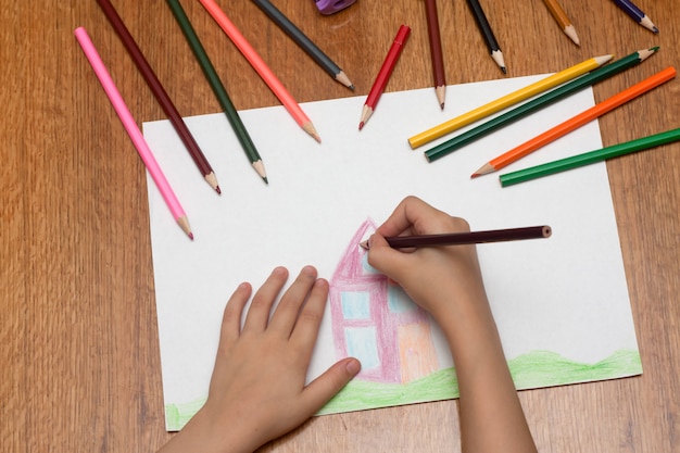 Child drawing with bright pencils on paper