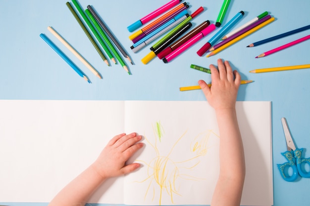 child draws blue baclground top view