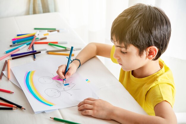 Photo child draws his family on a piece of paper with colored pencils. concept of child psychology.