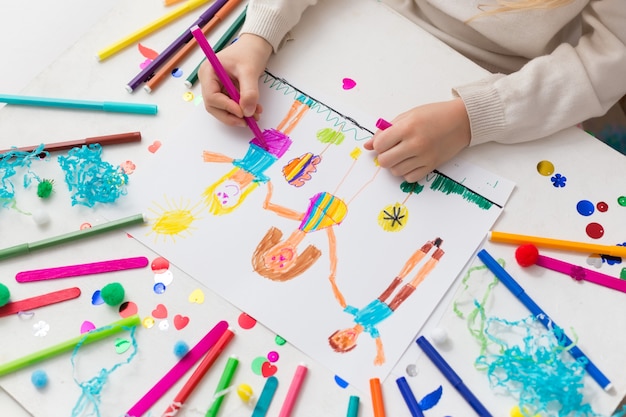 Child draws his friends with markers