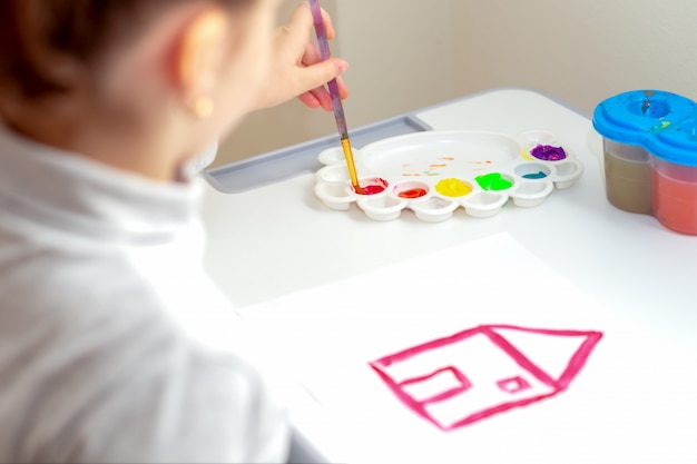 Child draws house with watercolors