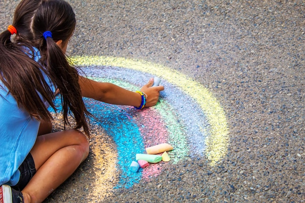 Un bambino disegna un arcobaleno sull'asfalto messa a fuoco selettiva