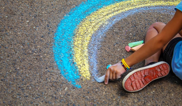 A child draws a rainbow on the asphalt selective focus