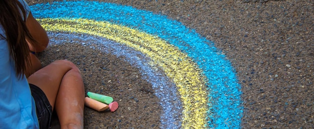 Photo a child draws a rainbow on the asphalt selective focus