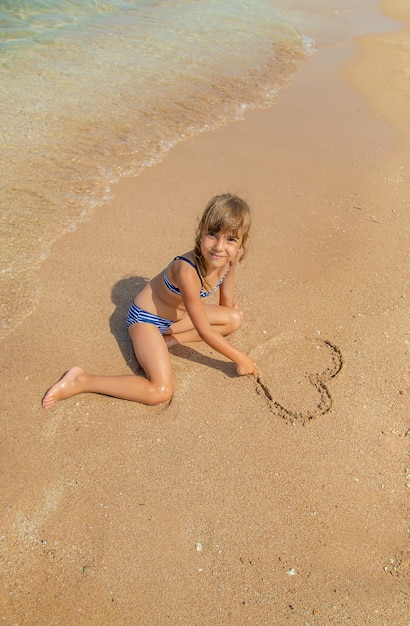 Child draws in the sand on the beach