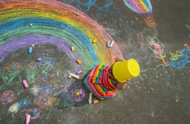 The child draws with chalk on the asphalt. Selective focus. Kid.