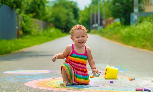 The child draws with chalk on the asphalt. Selective focus. Kid.