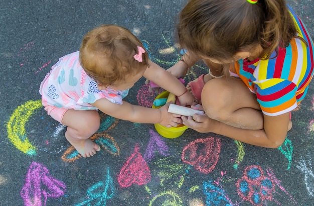 The child draws with chalk on the asphalt