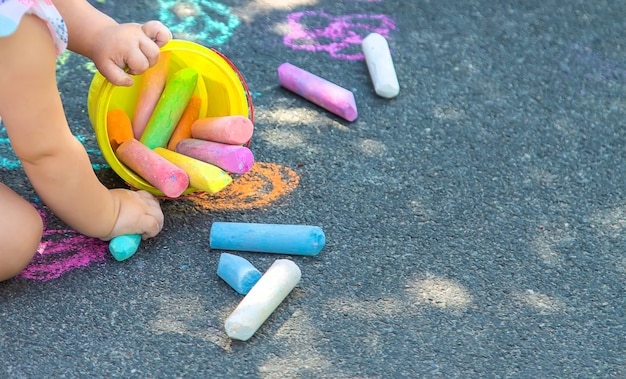 The child draws with chalk on the asphalt