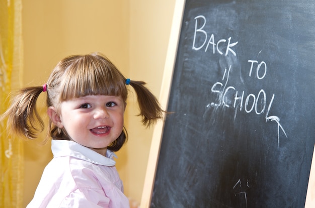 Photo child draws with chalk on the blackboard