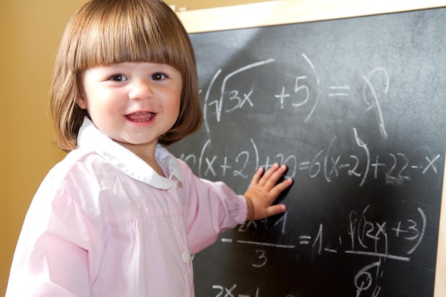 Photo child draws with chalk on the blackboard