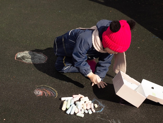 Photo child draws with chalk on the playground on a spring day