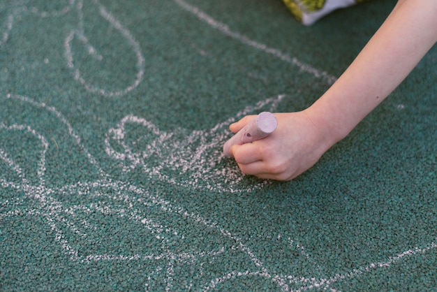 Child draws with chalk on the street. Special coating for drawing on the playground.