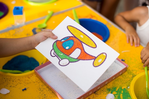 A child draws with colored sand picture. Cartoon characters.