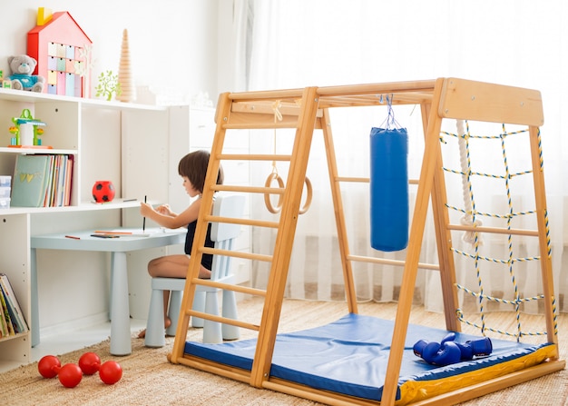 Foto il bambino disegna con le matite che si siedono al tavolo nella stanza dei bambini.