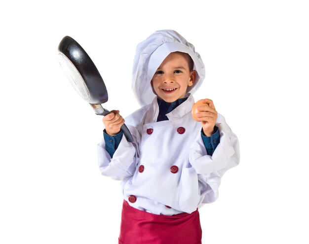 Child dressed as a chef holding fried pan