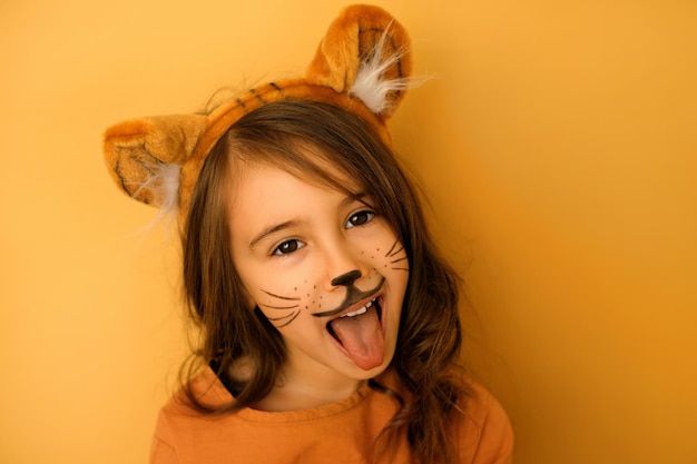 Child dressed up as a tiger with a painted mustache and a hat with ears growls and shows tongue