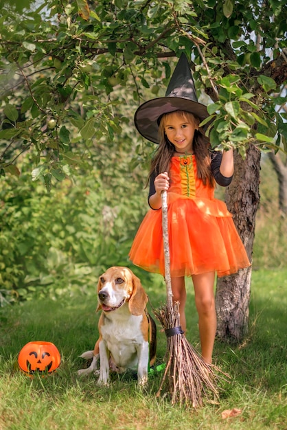 ハロウィーンで犬の友達と一緒に魔女の格好をした子供