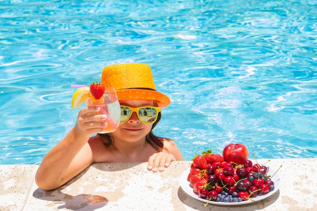Child drink cocktail Child in swimming pool with fruits Summer kids activity Summer vacation Healthy kids lifestyle
