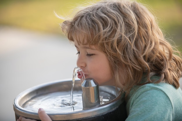 屋外の噴水から水を飲む子供