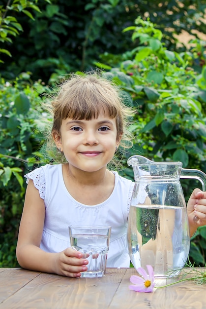 Photo the child drinks clean water in summer. selective focus.