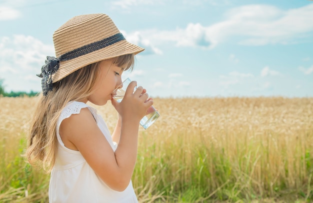 子供がフィールドの背景に水を飲む