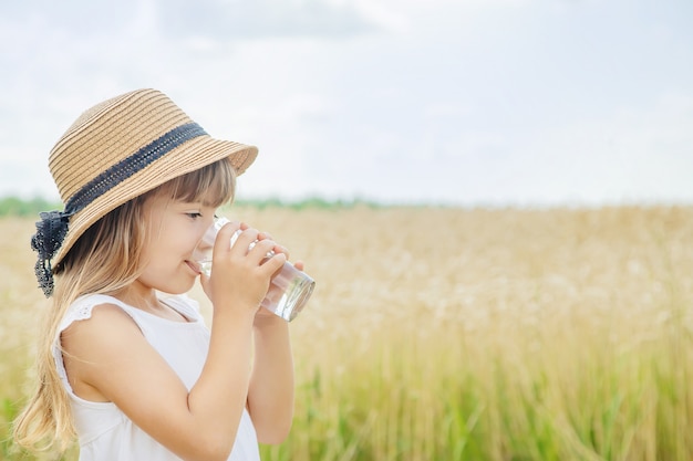 子供がフィールドの背景に水を飲む