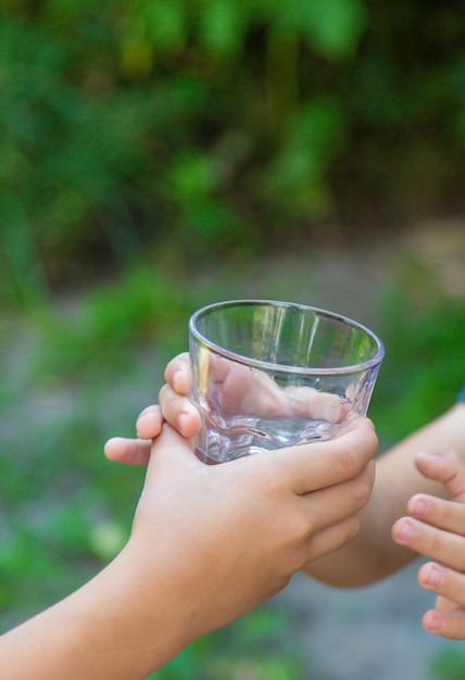 Foto il bambino beve l'acqua da un bicchiere messa a fuoco selettiva