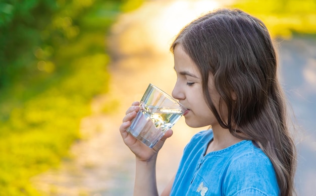 子供はグラスから水を飲む選択的な焦点