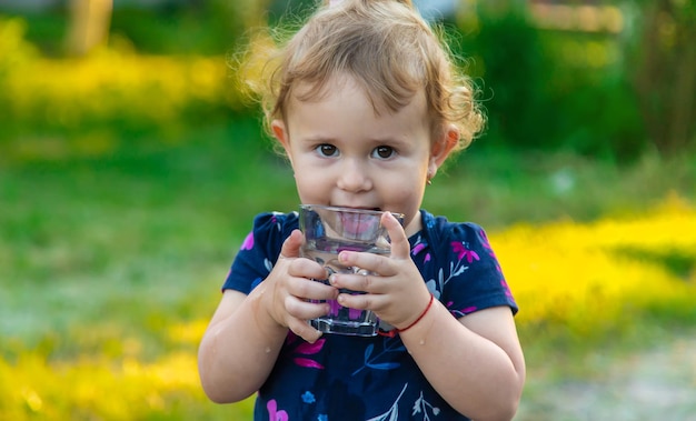 子供はグラスから水を飲む選択的な焦点