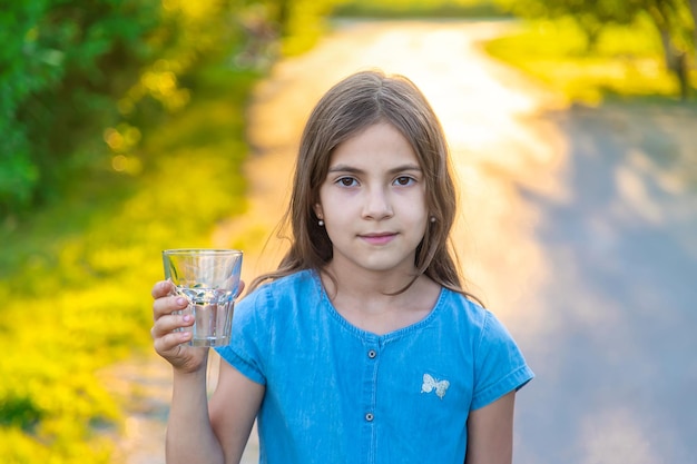 子供はグラスから水を飲む選択的な焦点