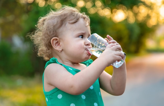 子供はグラスから水を飲む選択的な焦点