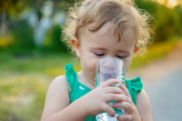 子供はグラスから水を飲む選択的な焦点