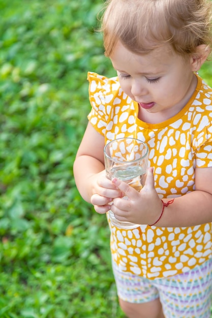 子供はグラスから水を飲む選択的な焦点