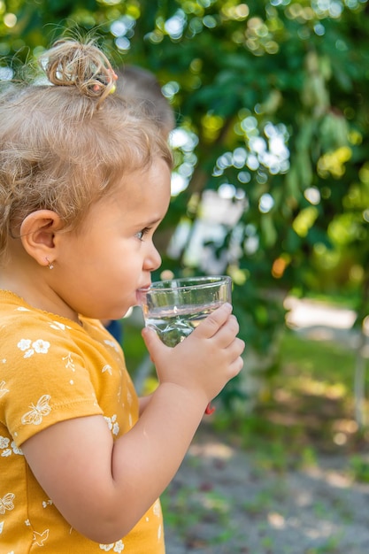 子供はグラスから水を飲む選択的な焦点